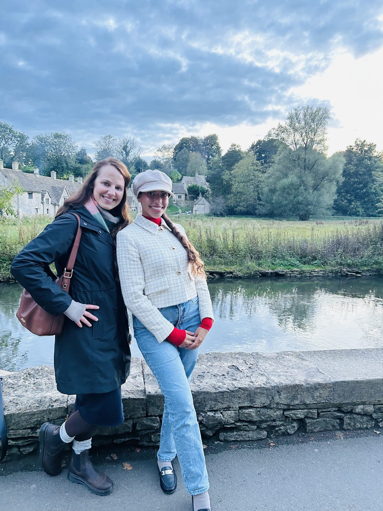 Two travelers standing beside the water in a Cotswolds village