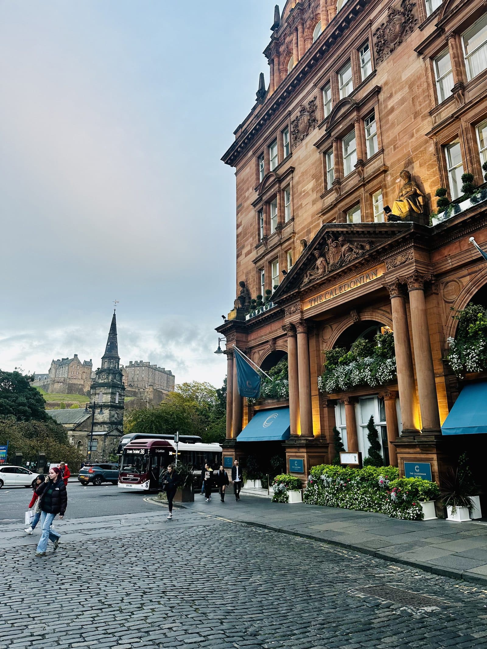 A grand red sandstone hotel on an Edinburgh street at dusk