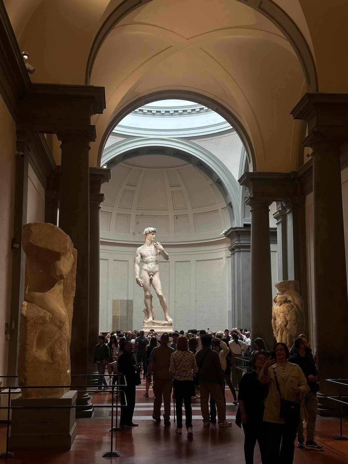 Michelangelo's David at the end of the gallery in the Accademia, with visitors gathered below