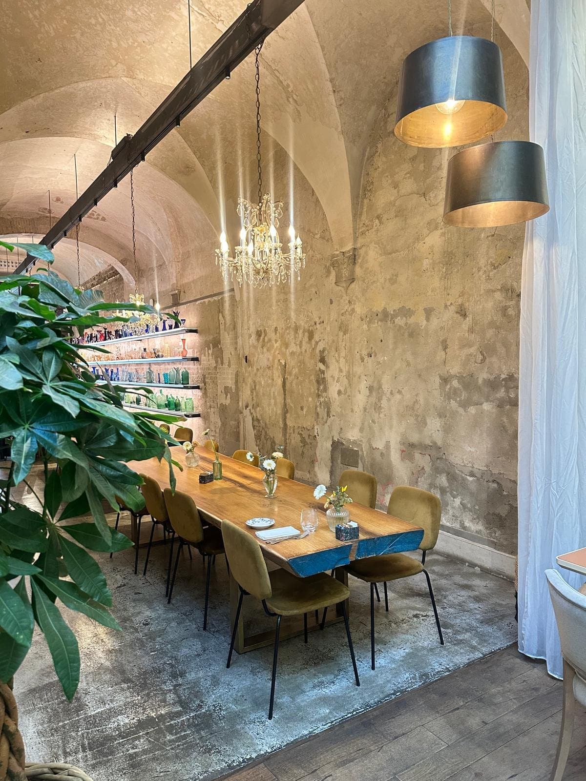 A long table laid under a vaulted ceiling and chandelier in a Florence dining room