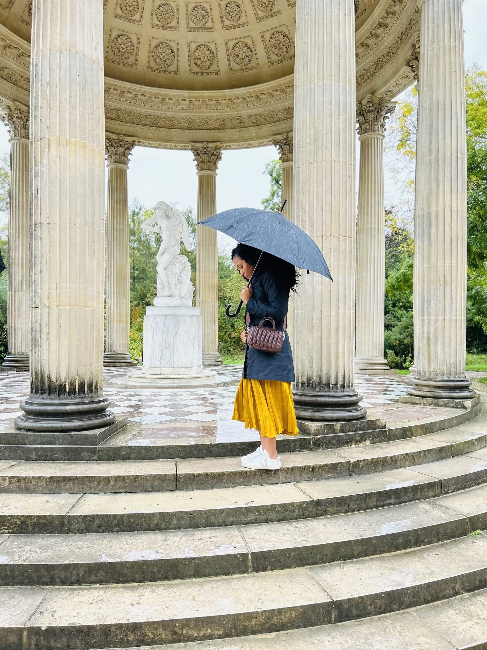 A colonnade in the gardens of Versailles, a figure small beneath the columns