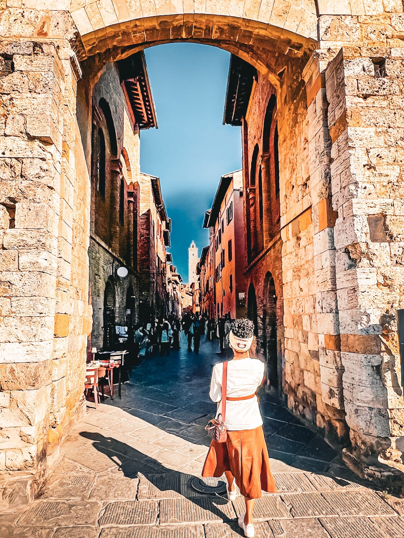 A medieval stone arch opening onto a narrow street of shops