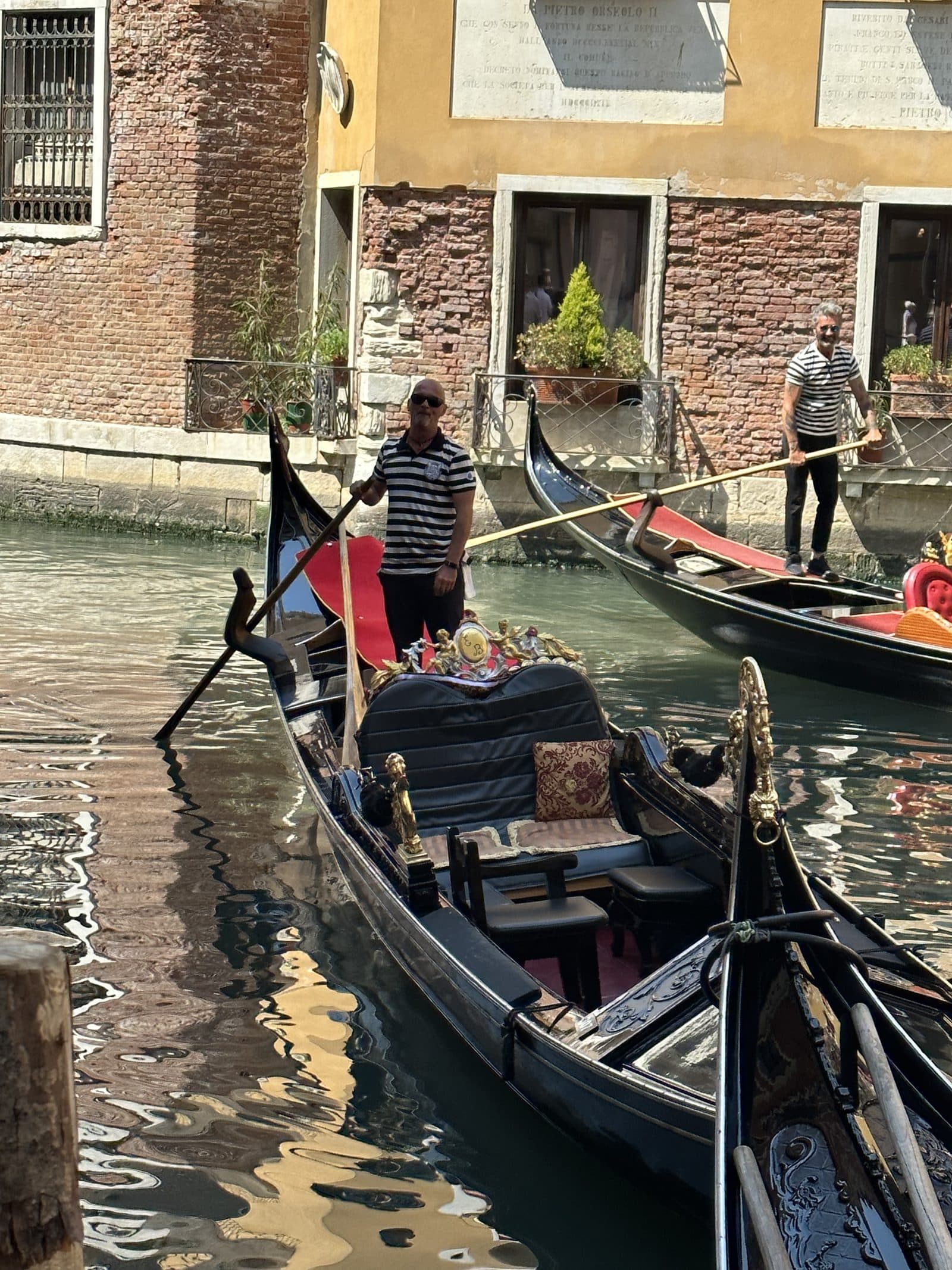 A gondolier steering along a narrow Venetian canal between old brick walls