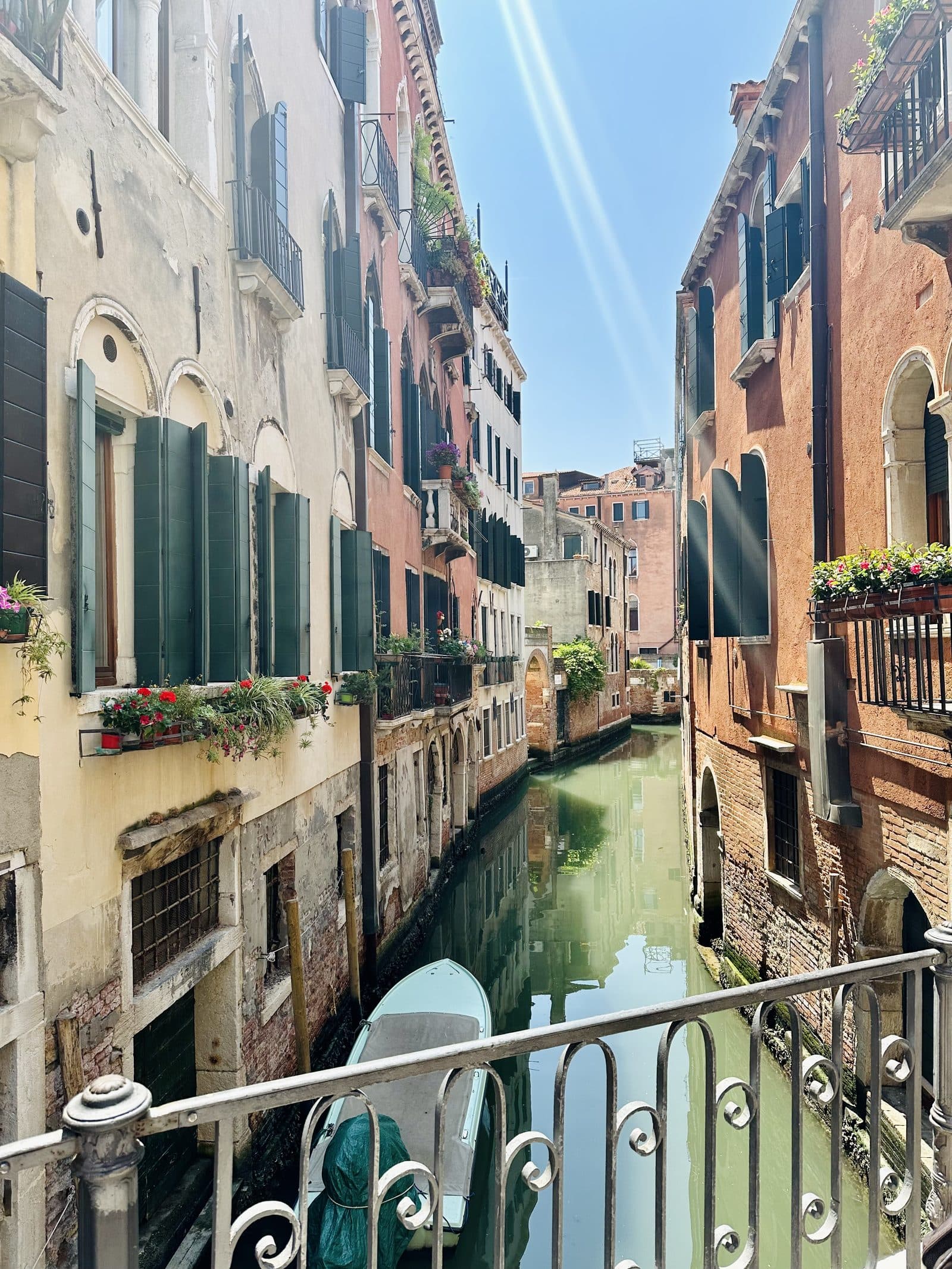 A quiet Venetian side canal seen from a bridge, with washing lines and shuttered windows