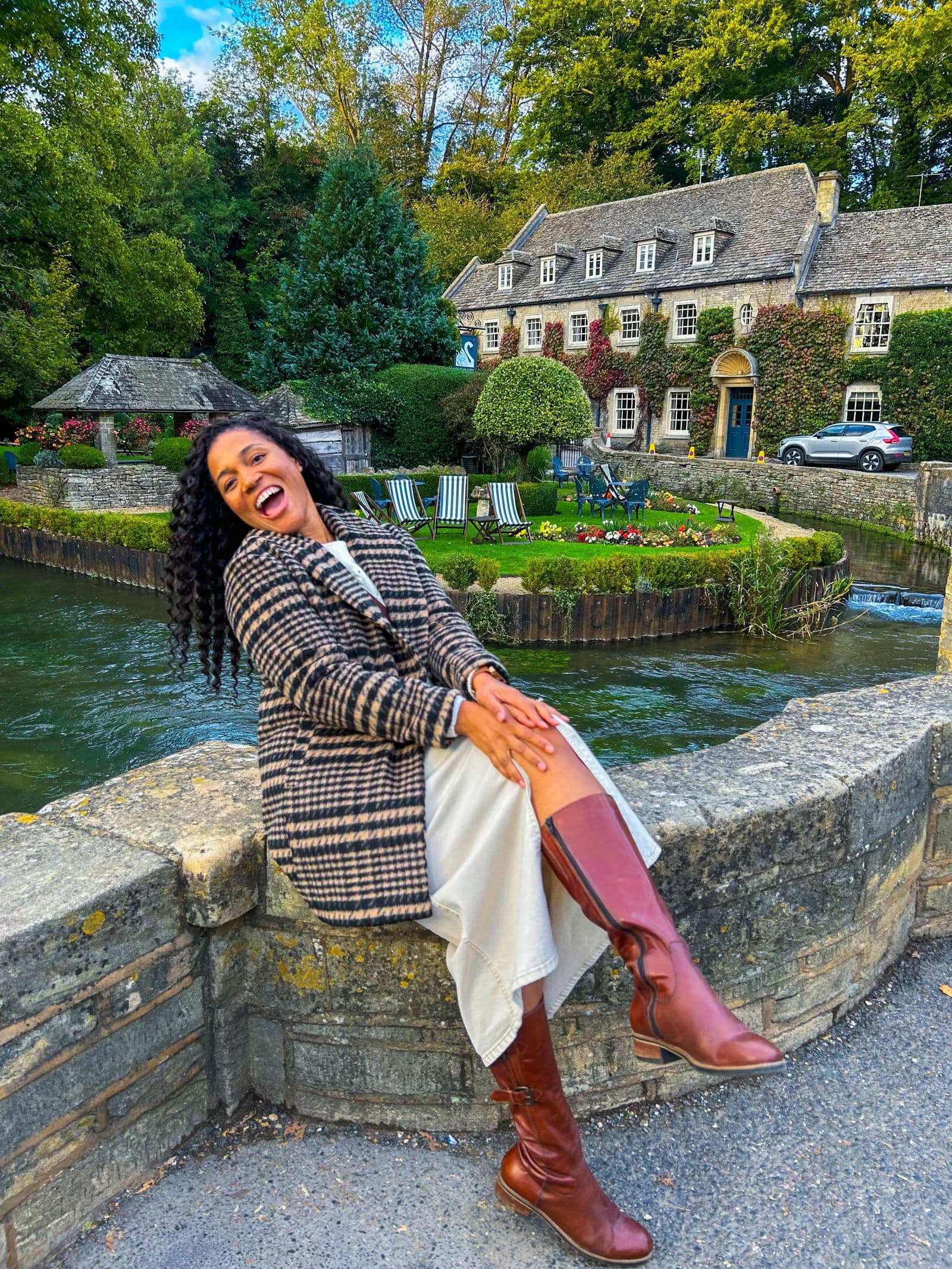 Kerry-Ann Stephens laughing on the bridge wall beside the water at Bibury