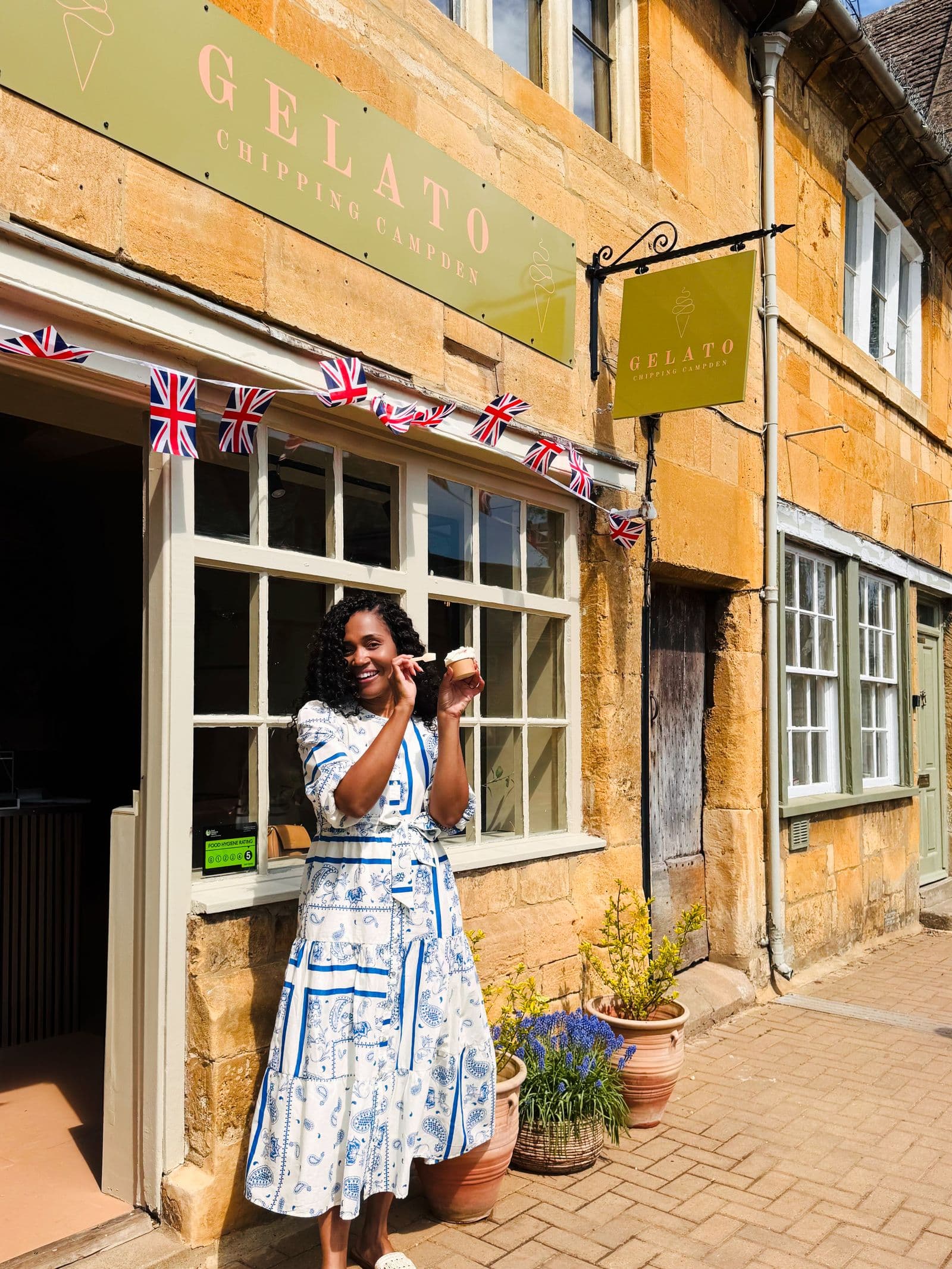 Kerry-Ann Stephens outside a gelato shop on a Cotswolds high street hung with small Union Jacks