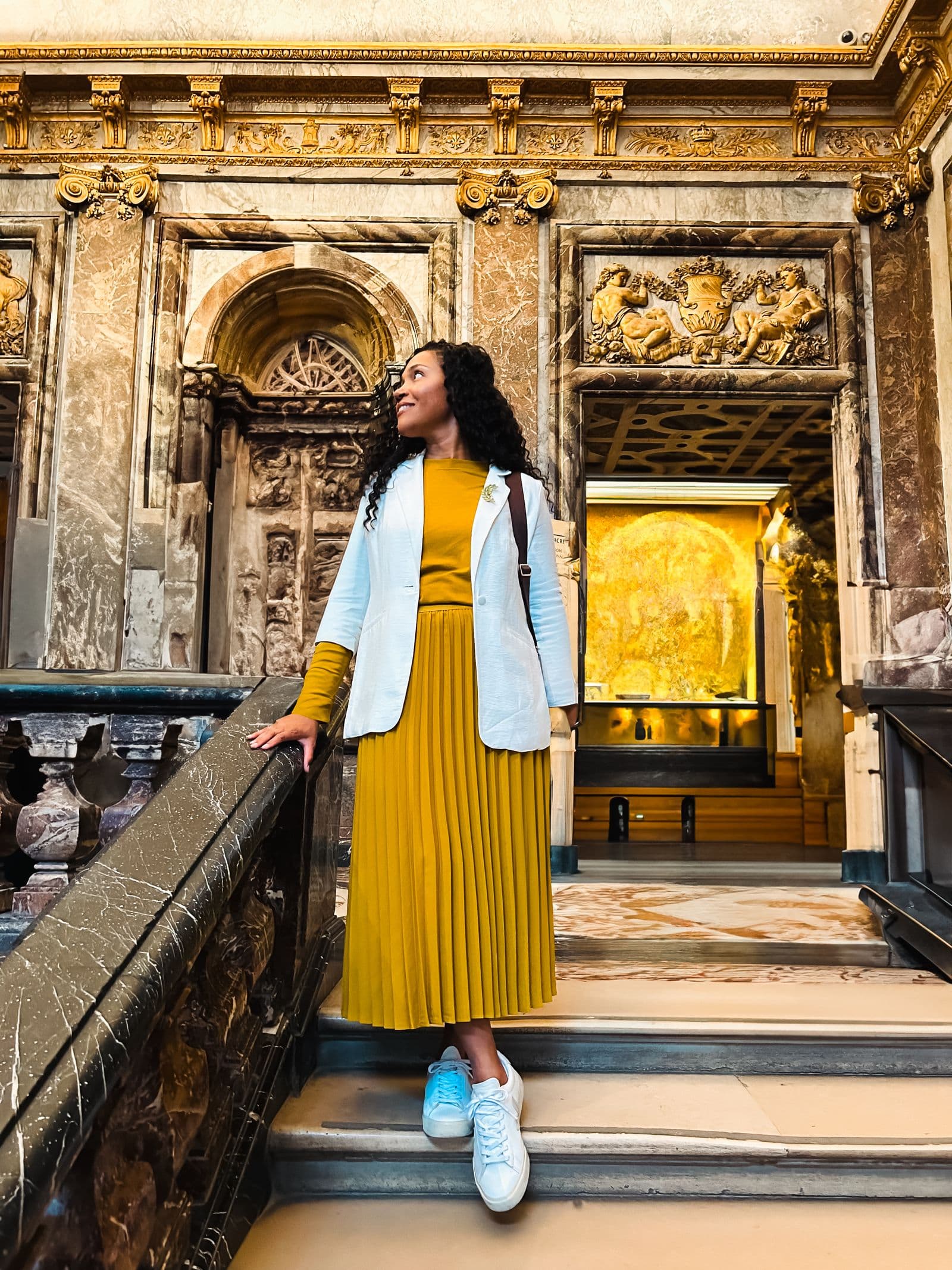 Kerry-Ann Stephens on a marble staircase beneath a heavily gilded ceiling