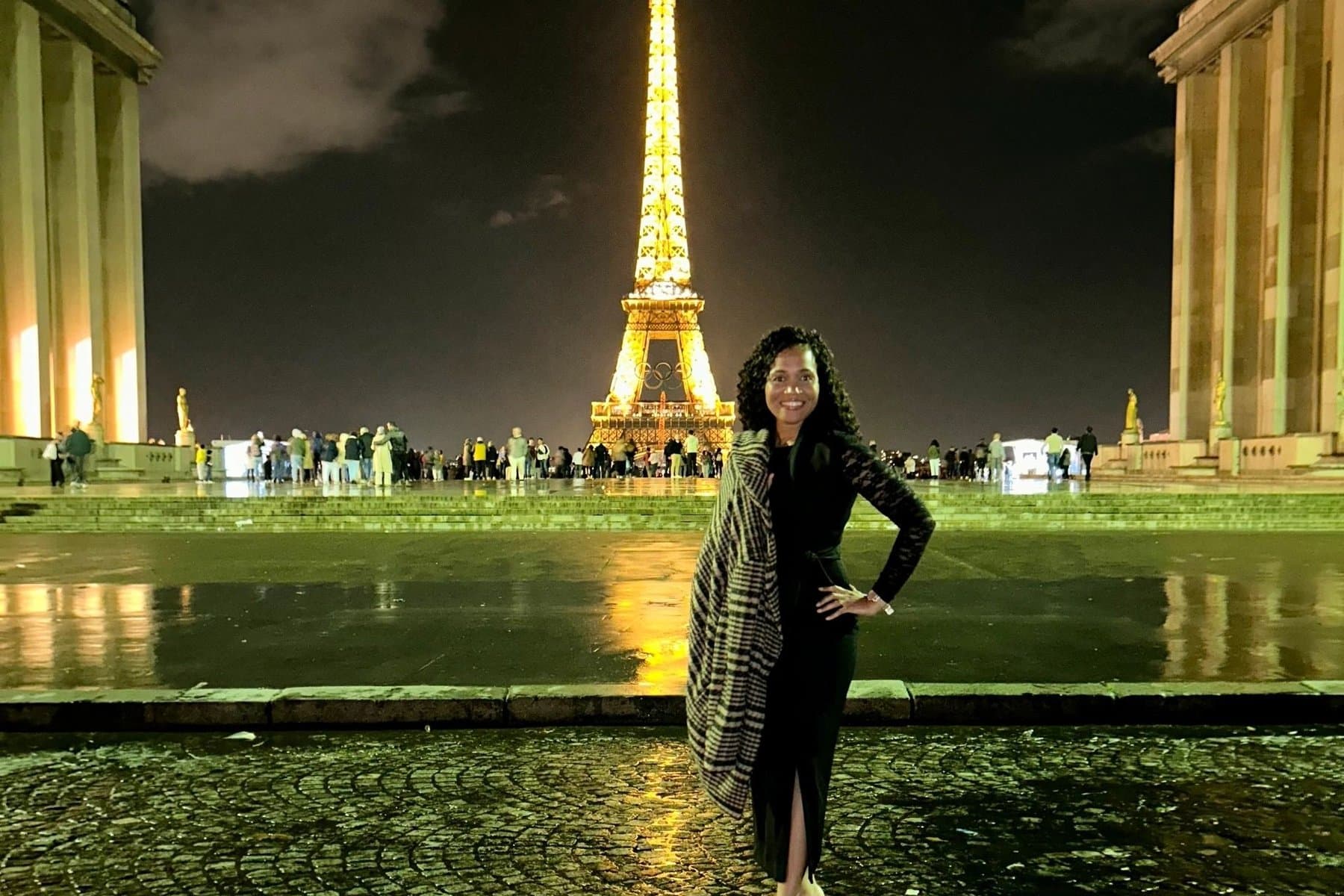 The Eiffel Tower lit at night, seen across the wet cobblestones of the Trocadéro
