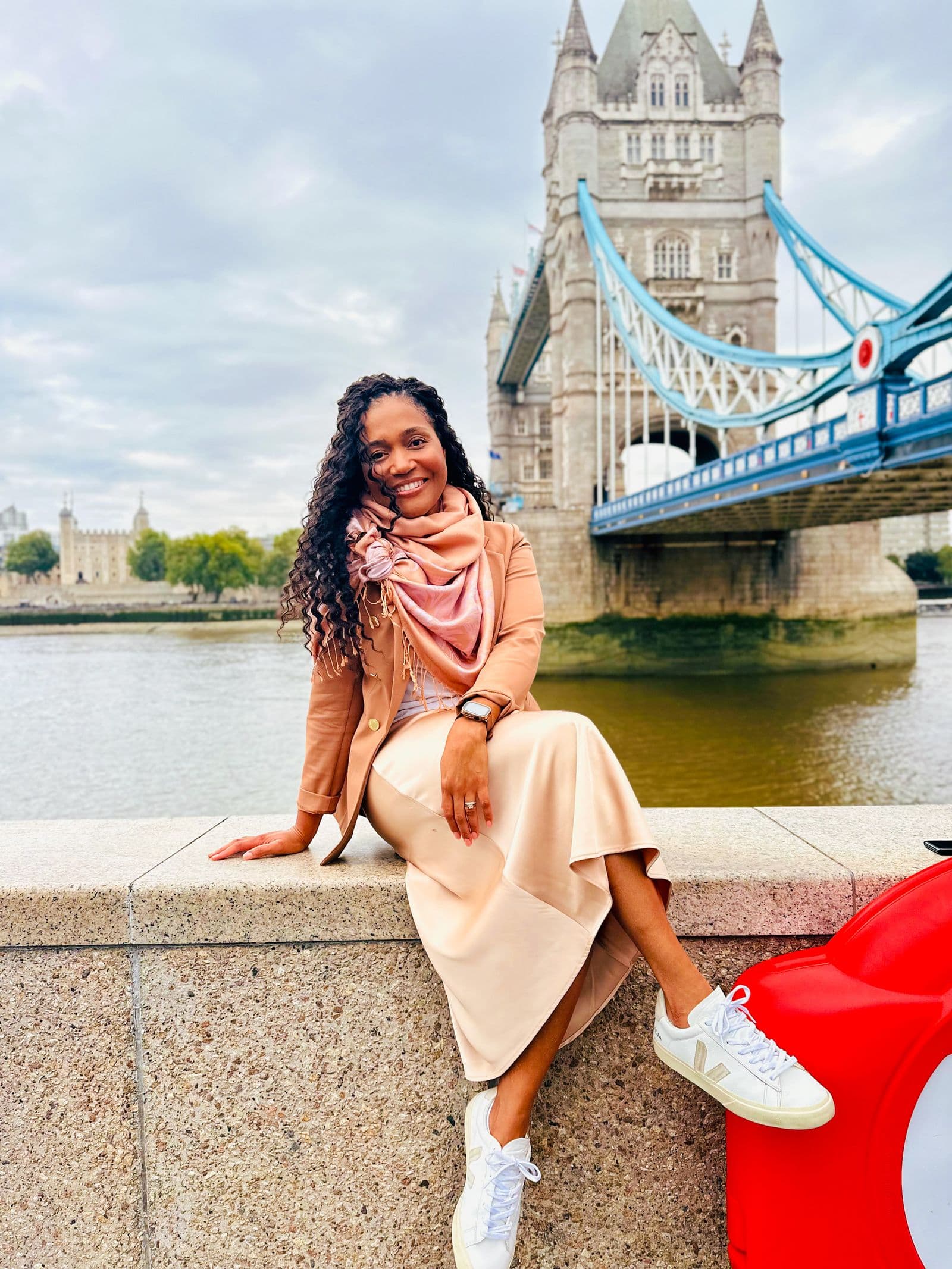 Kerry-Ann Stephens sitting on the river wall with Tower Bridge behind her
