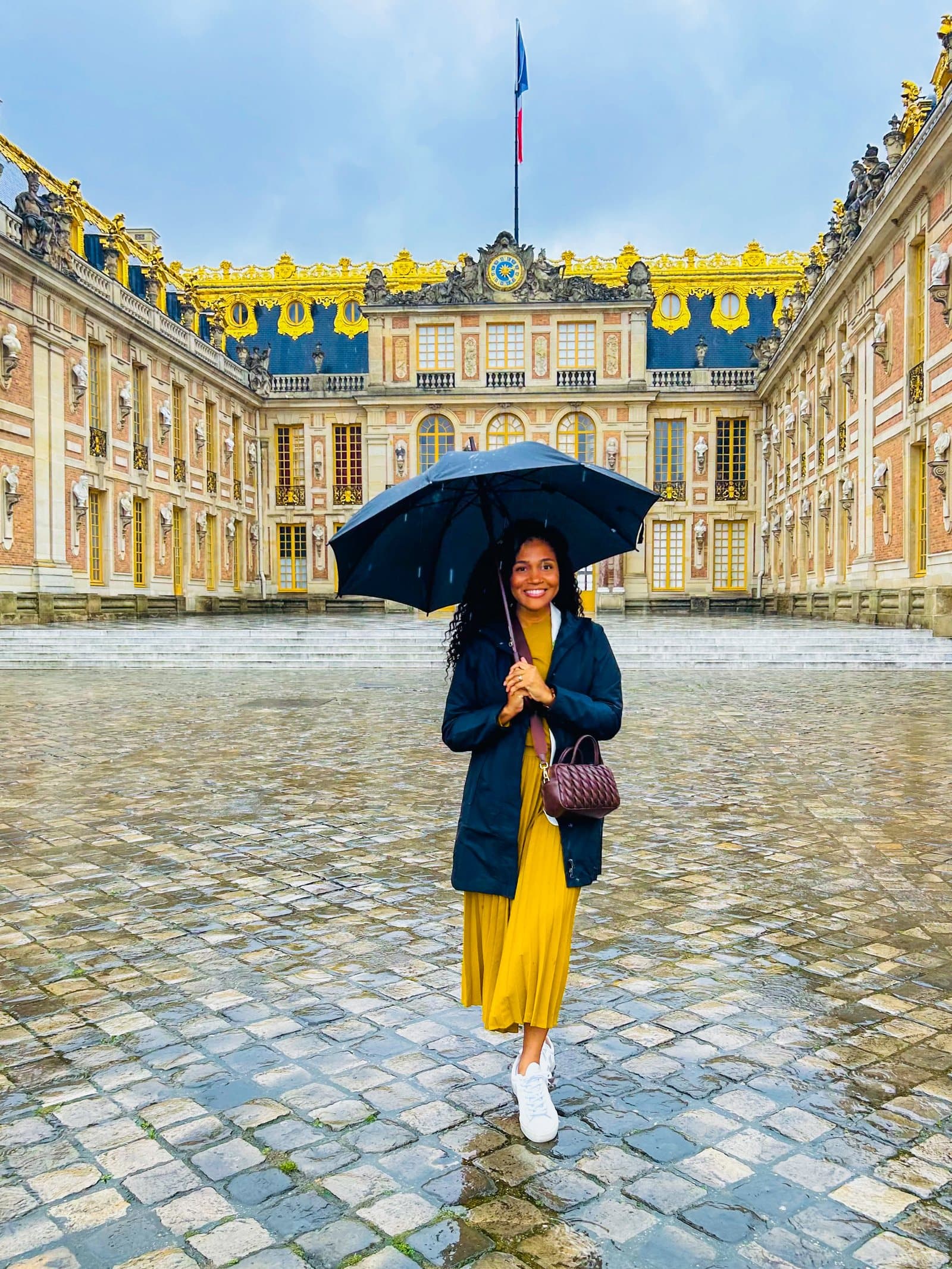 Kerry-Ann Stephens with an umbrella in the cobbled forecourt of the Château de Versailles