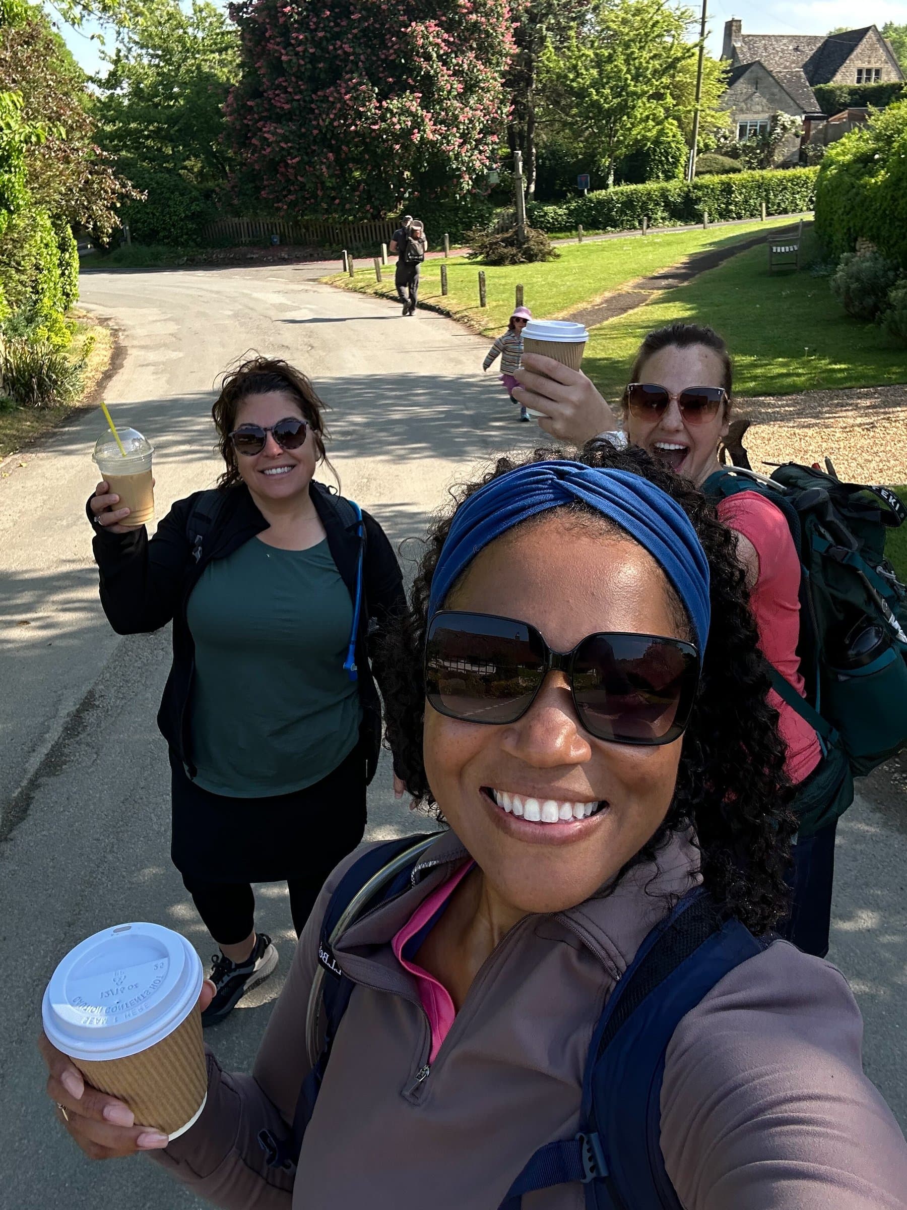 A group of walkers with backpacks pausing with coffee on a village lane