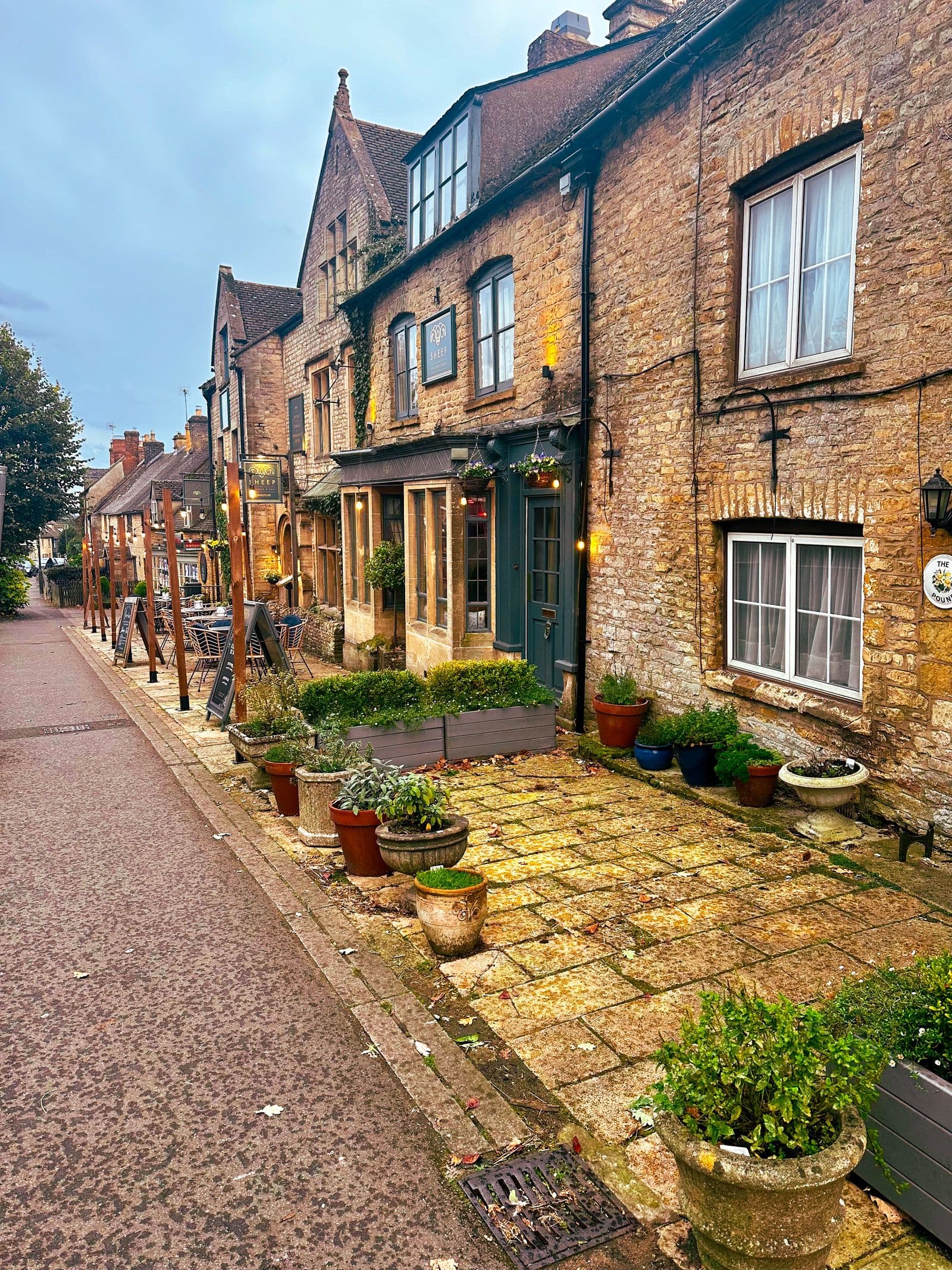 A row of stone cottages with pots of flowers along a narrow village street