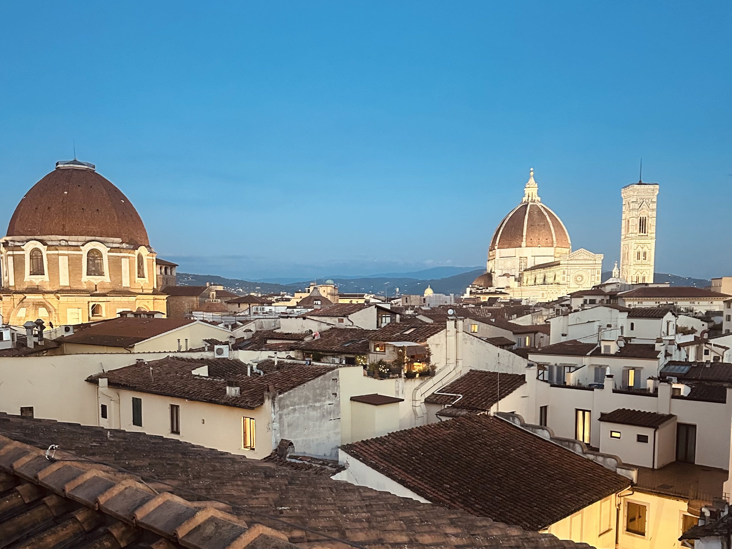 The Duomo and its campanile above the terracotta rooftops of Florence in the evening