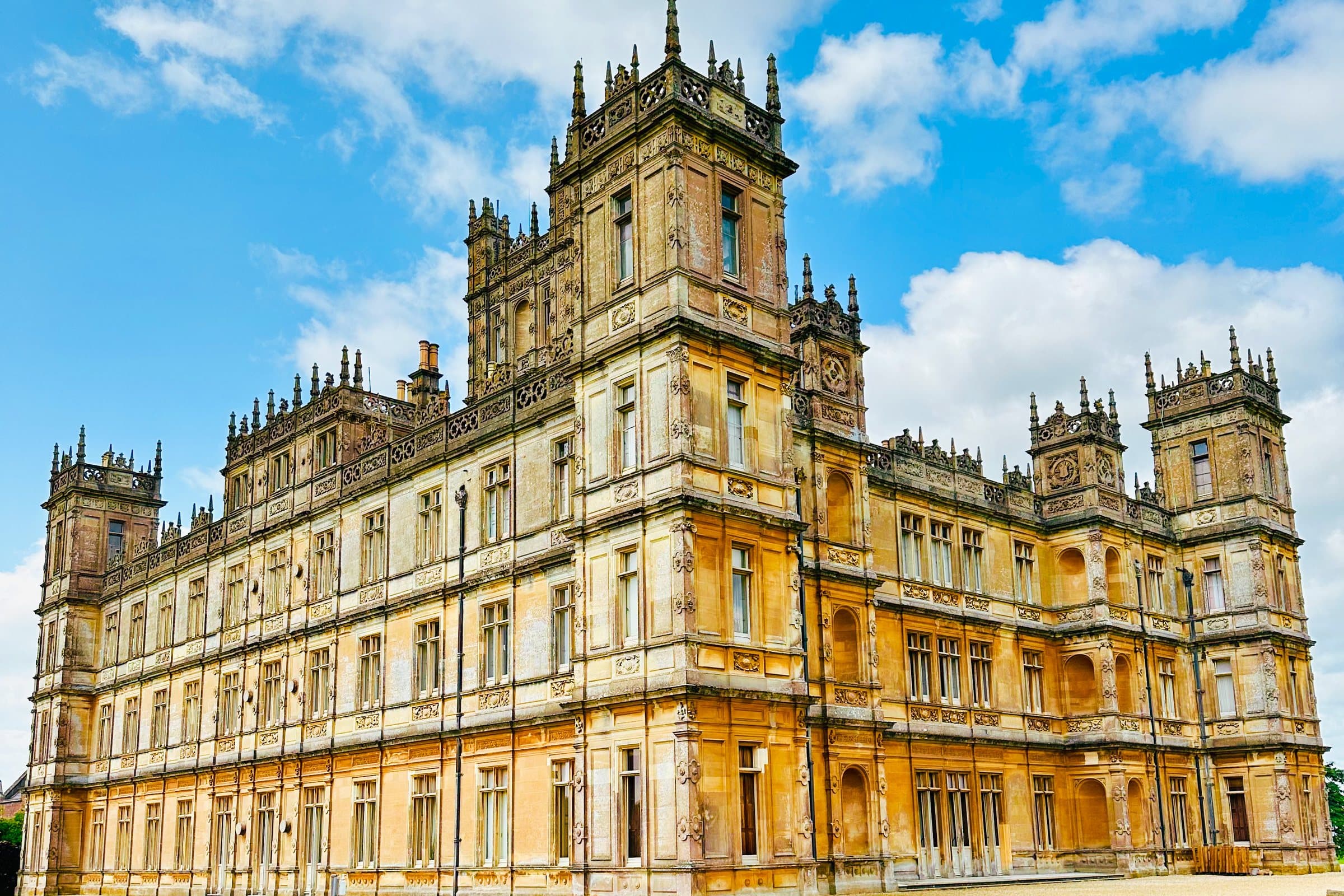 Highclere Castle rising above its lawn under a blue sky