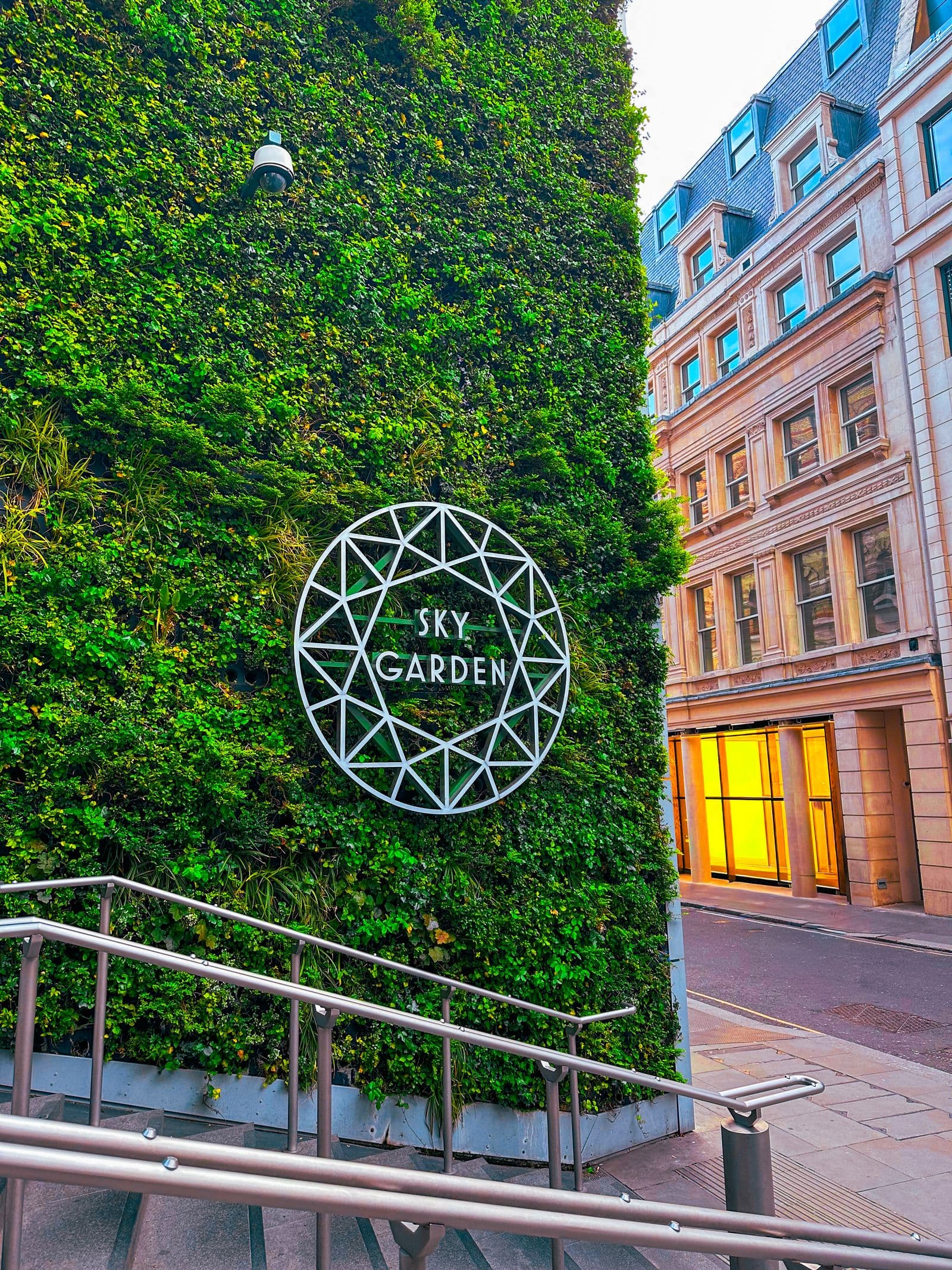 The ivy-covered wall and circular sign at the entrance to the Sky Garden in London