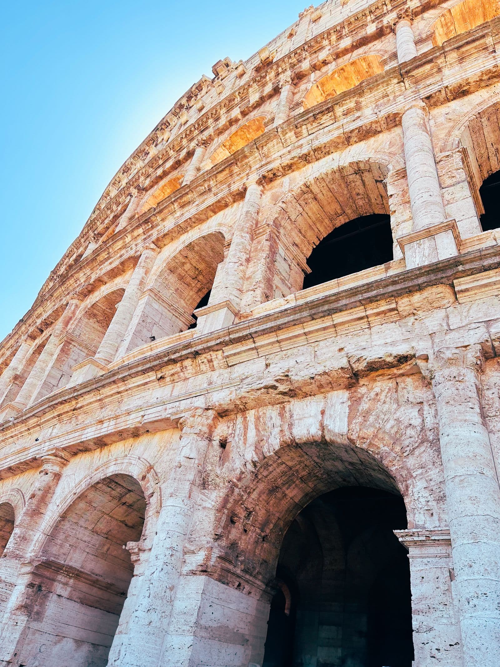 The tiered stone arches of the Colosseum seen from close below