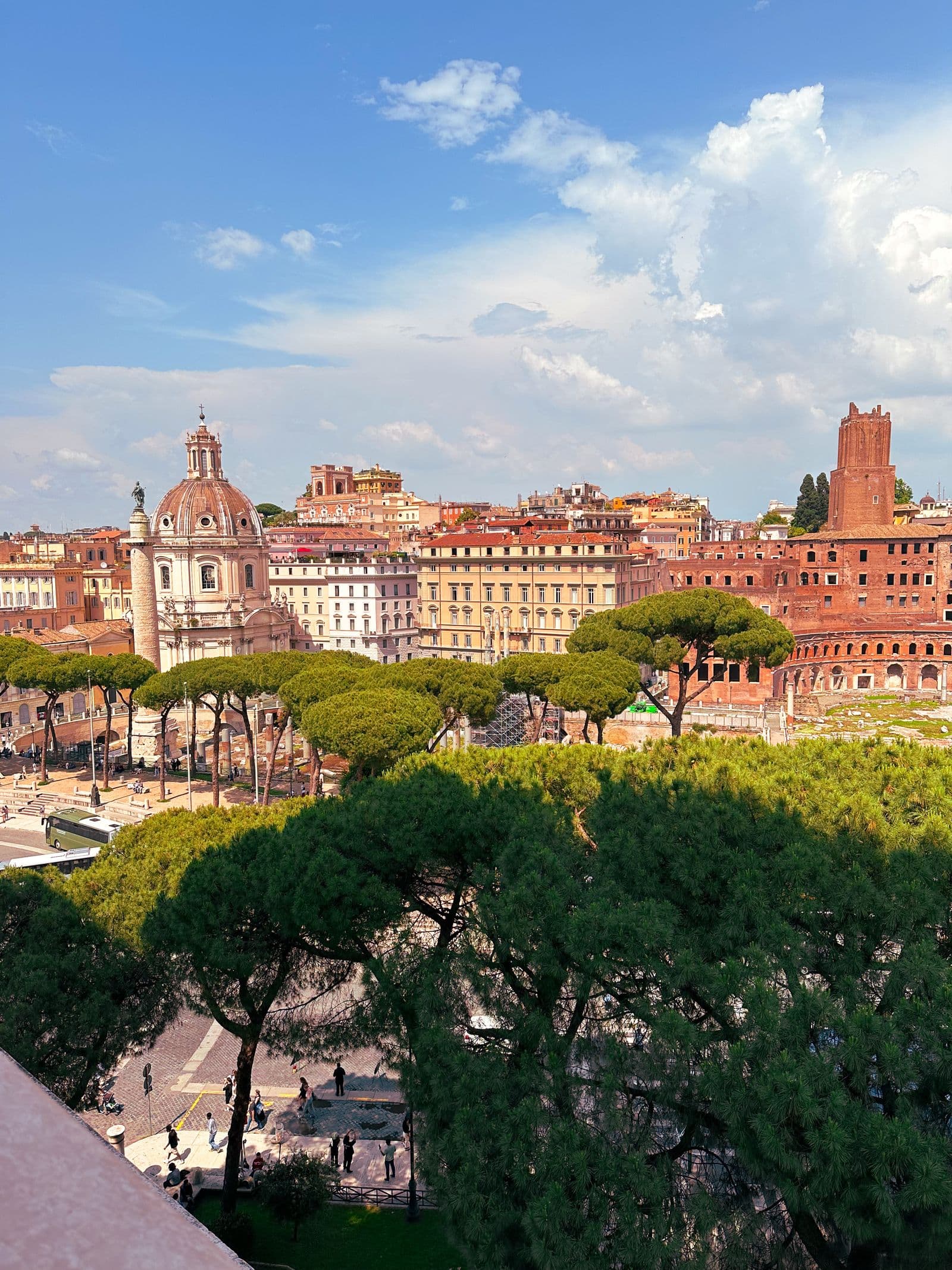 The ruins of Trajan's Forum with umbrella pines and Roman rooftops beyond