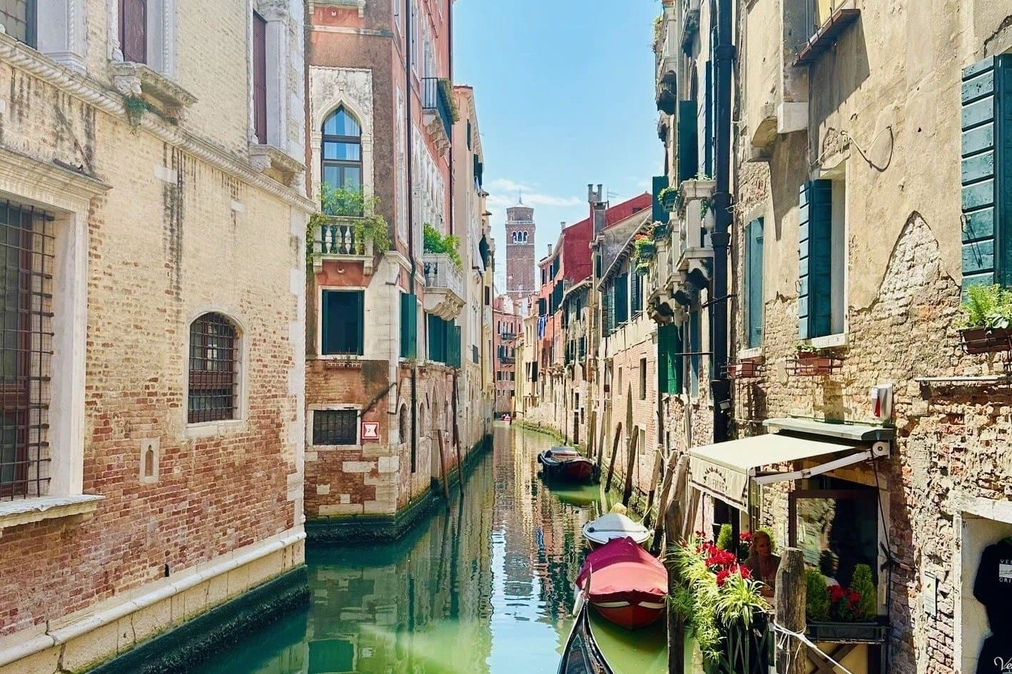 A quiet Venetian side canal with a moored gondola and flower boxes