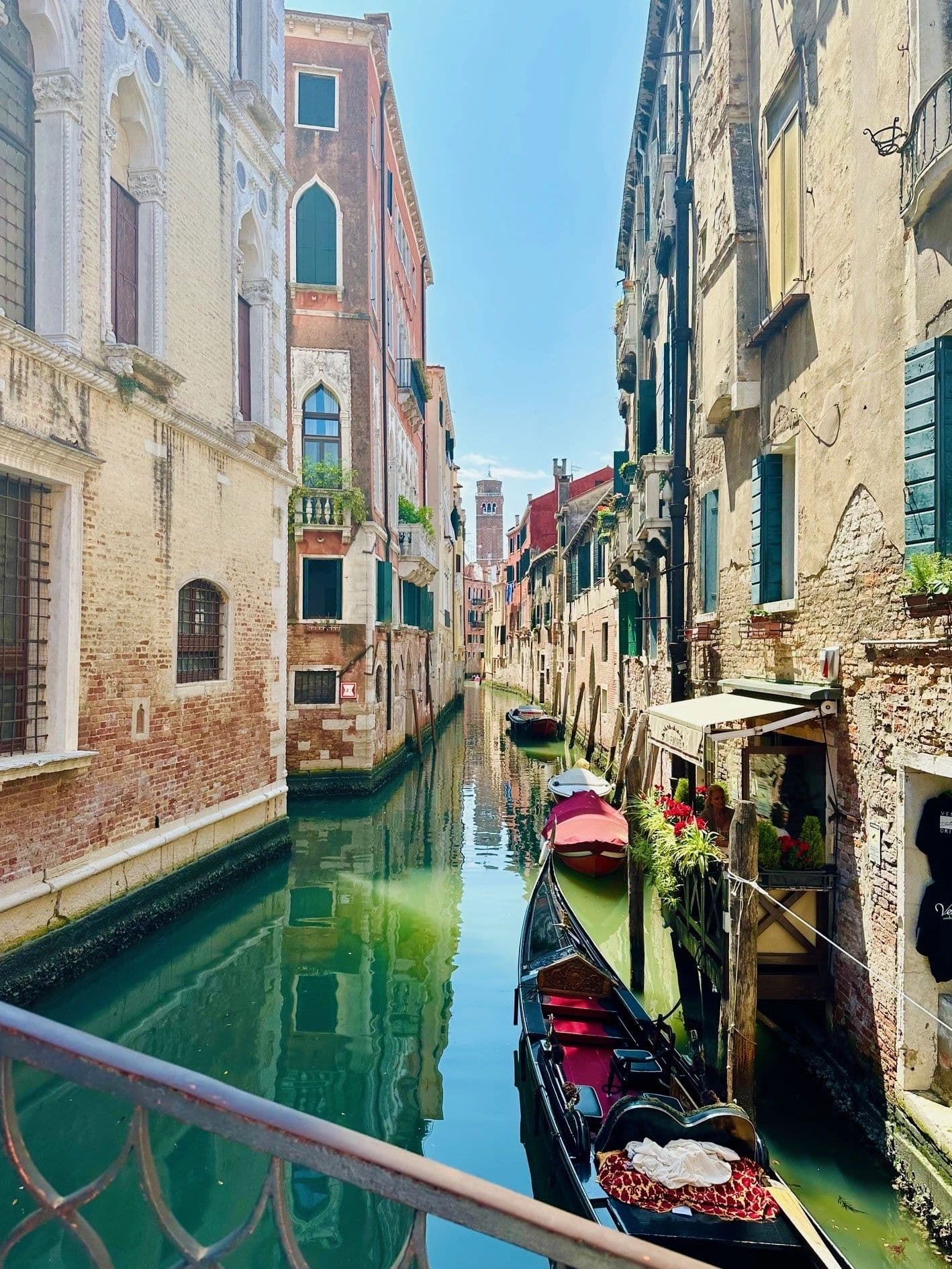 A quiet Venetian side canal with a moored gondola and window boxes of geraniums